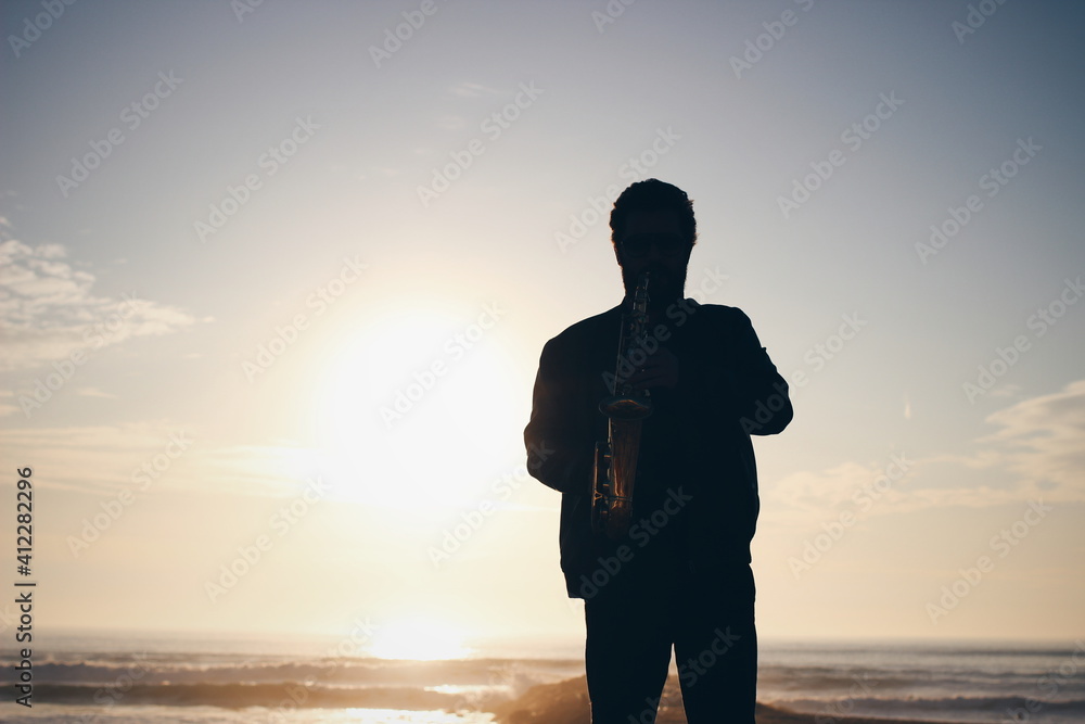 Backlit saxophone player in front of the ocean