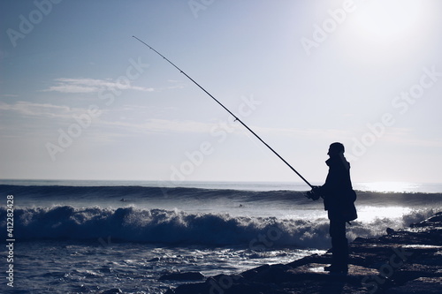 Fisherman on a pier with angry sea