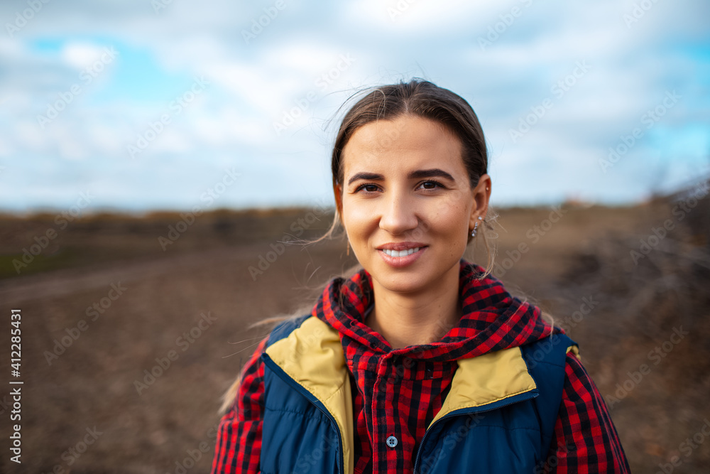 Fototapeta premium Outdoor portrait of young smiling girl on blurred background of sky and field.