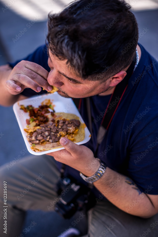 Mexicano comiendo tacos de guisos sentado en mexico