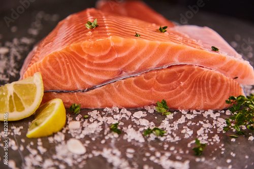 Fresh raw fillet of sea fish salmon or trout with spices and herbs on a dark background. The concept of cooking fresh fish in a restaurant or at home in the kitchen