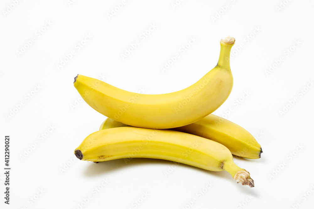Bananas on a white background. Fresh yellow bananas. One banana is on top of the others. Exotic fruit