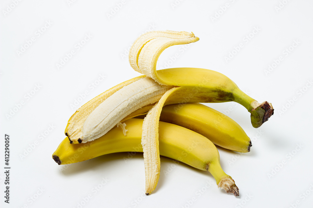 Bananas on a white background. Fresh yellow bananas. A peeled banana lies on top of whole bananas. Exotic fruit