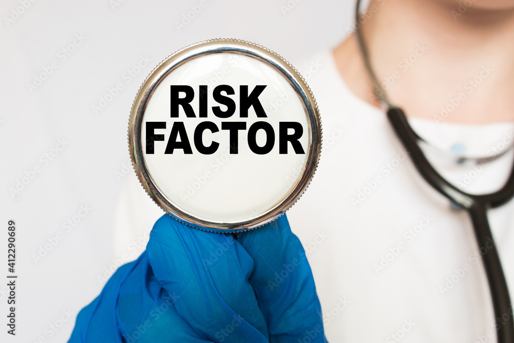 The doctor's blue - gloved hands show the word RISK FACTOR - . a gloved hand on a white background. Medical concept. the medicine The doctor's blue - gloved hands show the word RISK FACTOR - . a gloved hand on a white background. Medical concept. the medicine