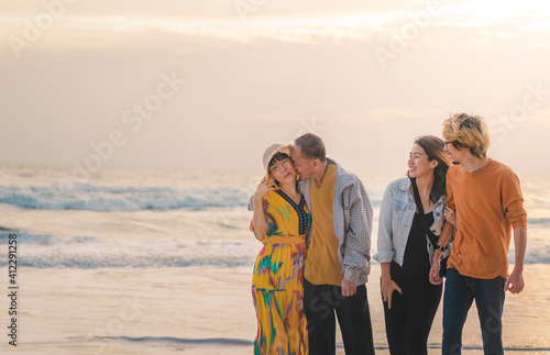 Happy asian family standing on the beach at sunrise time.