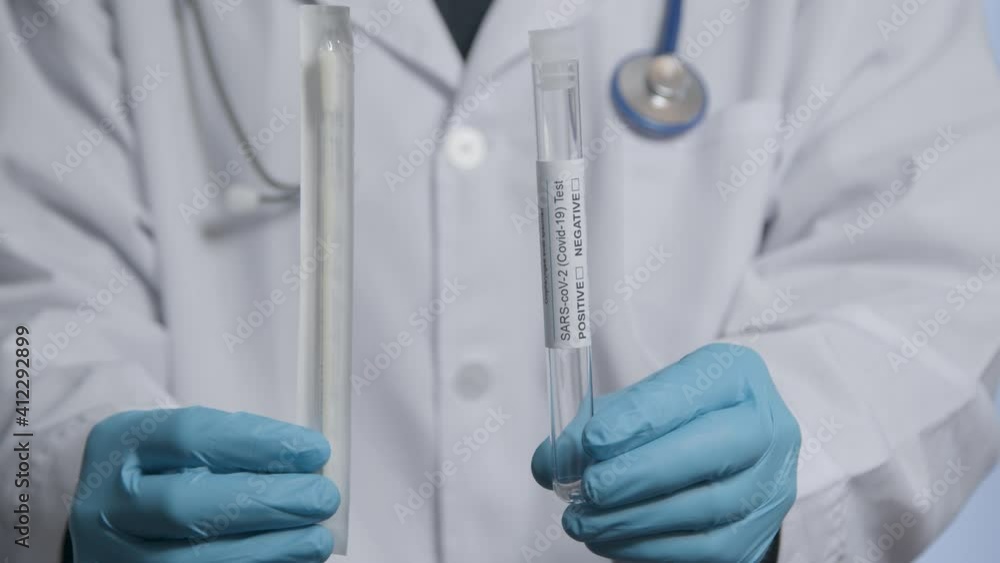 Close Up Shot of Medical Professionals Hands Holding COVID Test Tube and Swab Close Up Shot of Medical Professionals Hands Holding COVID Test Tube and Swab