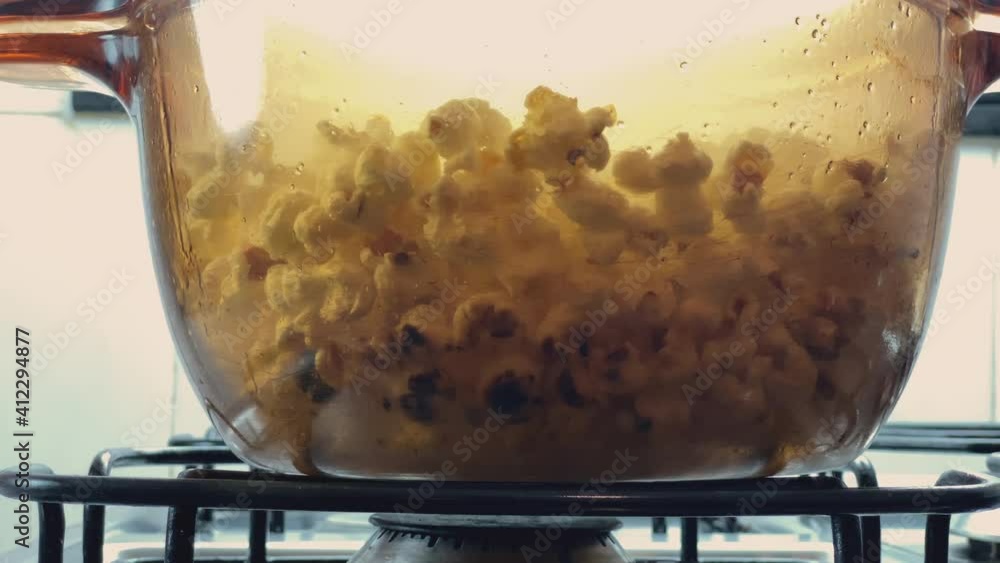 Burnt popcorn! Hot glass pan with popping popcorn seeds from gas stove