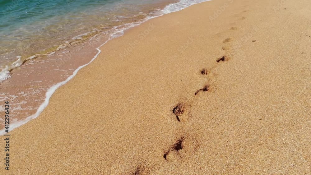 Aerial view of traffic over the golden seashell beach and azure sea. Footprints of two people in the sand Aerial view of traffic over the golden seashell beach and azure sea. Footprints of two people in the sand