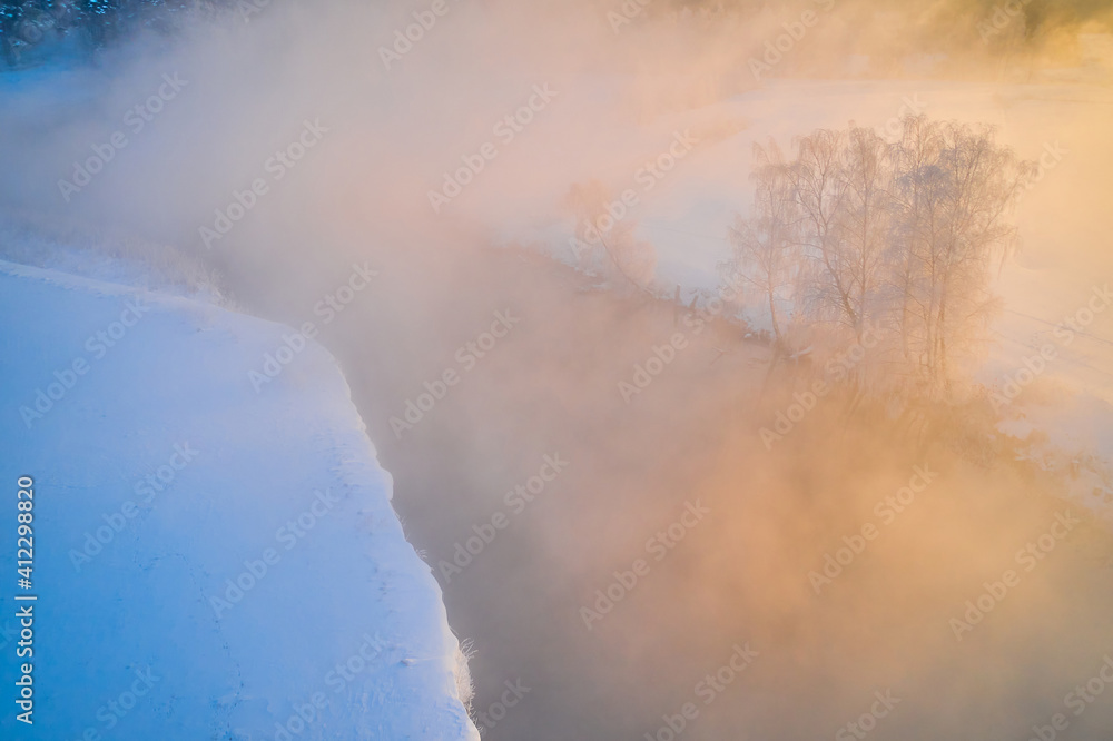 Fototapeta premium Magic sunlight illuminates trees covered with frost. Crystal white trees in winter morning near river