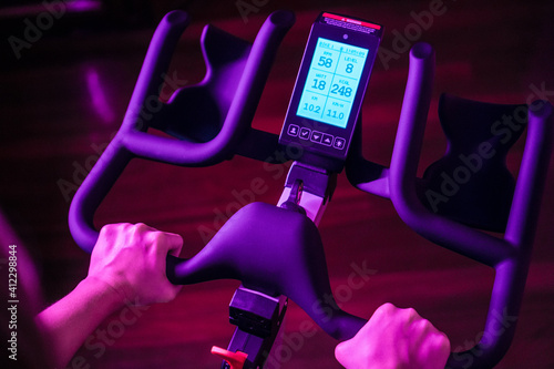 Girl or woman doing a spinning session at home. Configure the parameters of her bike through the screen. Cardio exercise.