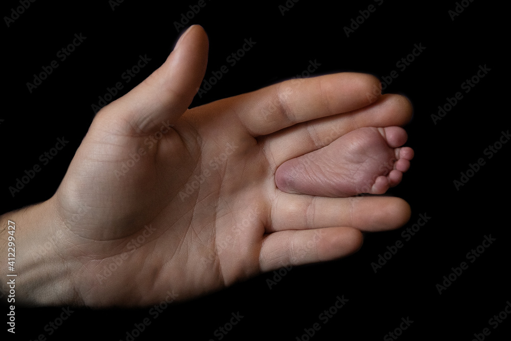 Fuß eines Babys mit der Hand eines Erwachsenen