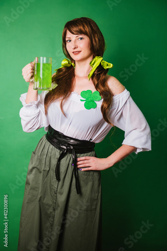 The girl celebrates st patrick's day. A woman in a medieval historical costume with a large mug of green beer.