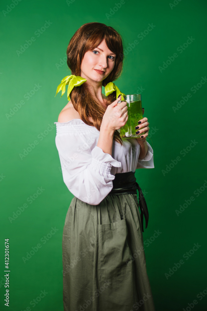 The girl celebrates st patrick's day. A woman in a medieval historical costume with a large mug of green beer. The girl celebrates st patrick's day. A woman in a medieval historical costume with a large mug of green beer.