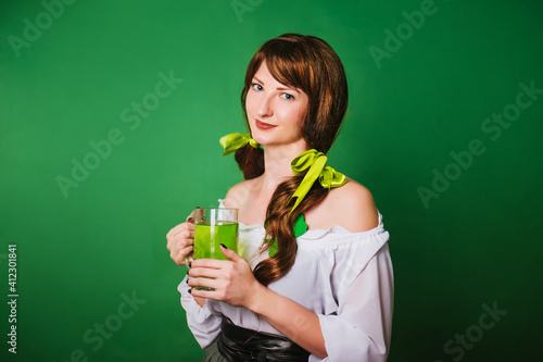 The girl celebrates st patrick's day. A woman in a medieval historical costume with a large mug of green beer.