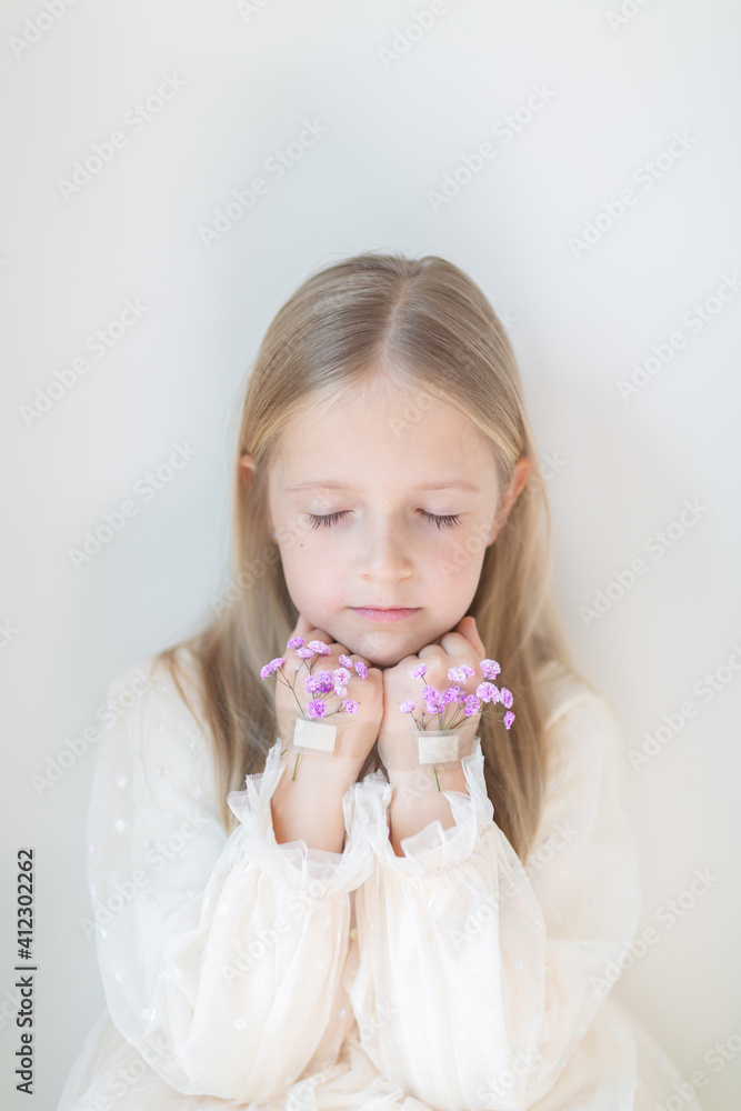 Close-up portrait of smiling little caucasian girl with gypsophila flowers isolated on grey background. Model in studio. Trendy creative idea Close-up portrait of smiling little caucasian girl with gypsophila flowers isolated on grey background. Model in studio. Trendy creative idea