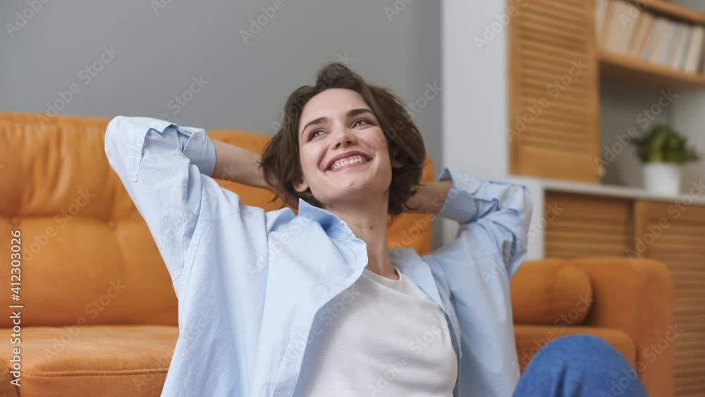 Smiling calm satisfied beautiful young woman 20s wears casual white t-shirt blue denim shirt sitting on sofa couch rest relax spend time in living room lounge at home in own house. Real estate concept Smiling calm satisfied beautiful young woman 20s wears casual white t-shirt blue denim shirt sitting on sofa couch rest relax spend time in living room lounge at home in own house. Real estate concept