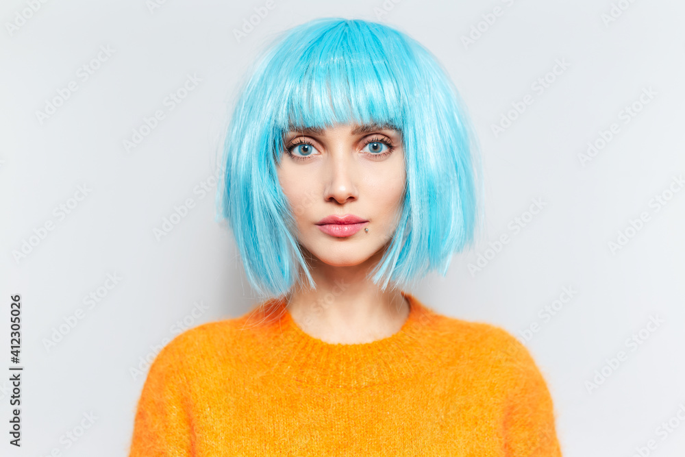 Studio portrait of young beautiful girl with blue eyes and bob haircut, wearing orange sweater on white background. Studio portrait of young beautiful girl with blue eyes and bob haircut, wearing orange sweater on white background.