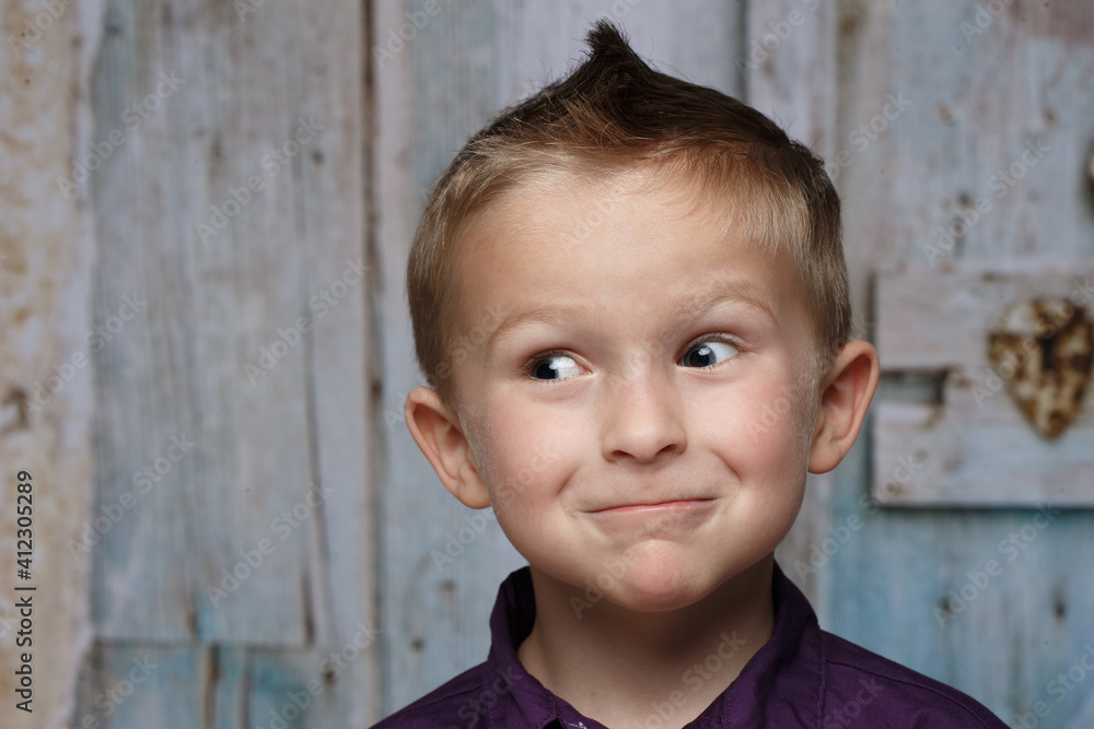 Young preschool Caucasian boy making funny face expression with eyes open wide looking off to the side