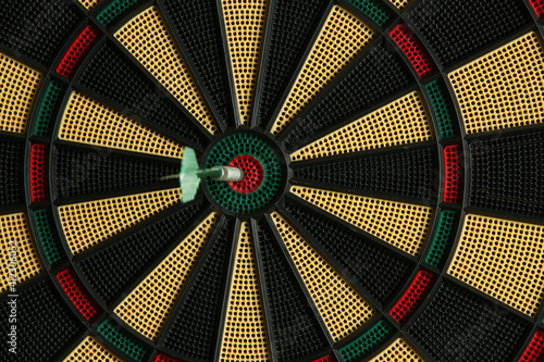 Darts target game. Close up image of dartboard with dart arrow hitting the center. Marketing and business concept.