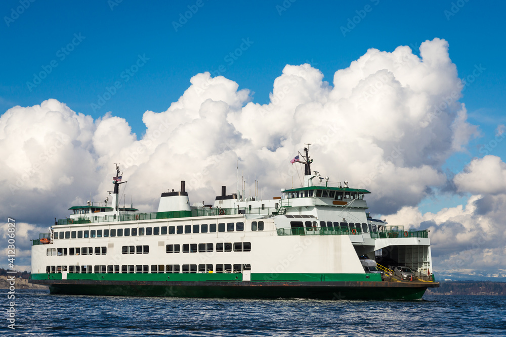 Car ferry under white billowing clouds  on calm water