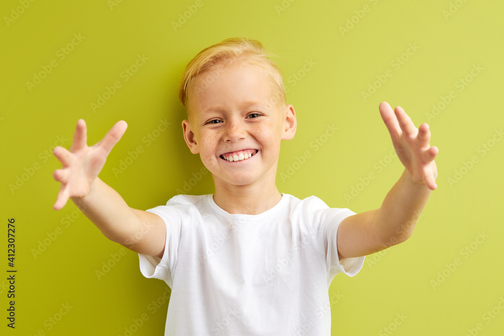 little boy with freckles spreading hands, trying to hug friend in school, positive cheerful child in casual T-shirt stand smiling at camera, isolated over green background little boy with freckles spreading hands, trying to hug friend in school, positive cheerful child in casual T-shirt stand smiling at camera, isolated over green background