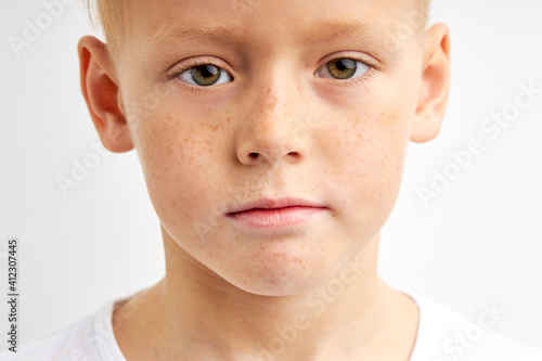 close-up portrait of teenager boy with shy diligent look, having green big eyes, seriously looking at camera isolated over white studio background