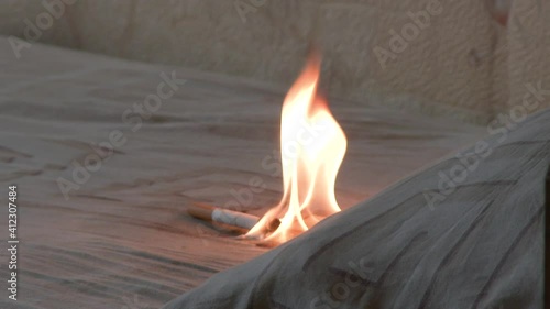 Burning cigarette with smoke in the bedroom on the bed leads to a fire. The process of developing a fire from a cigarette. Fire hazard concept of a house. Alcoholism and tobacco smoking