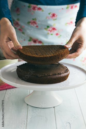 Woman adding second layer to chocolate cake photo