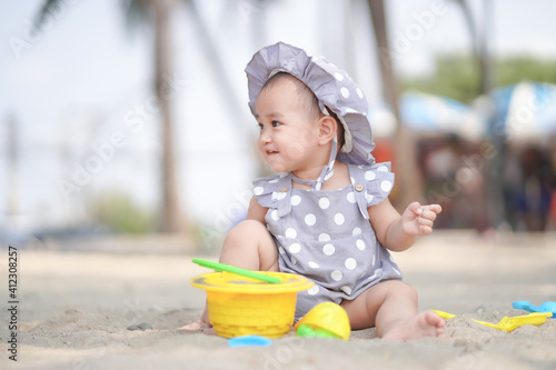 Asian cute baby girl playing on the sand beach on sunny day