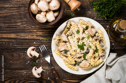 Pasta fusilli with Chicken and mushrooms In cream sauce. Top view on wooden table.