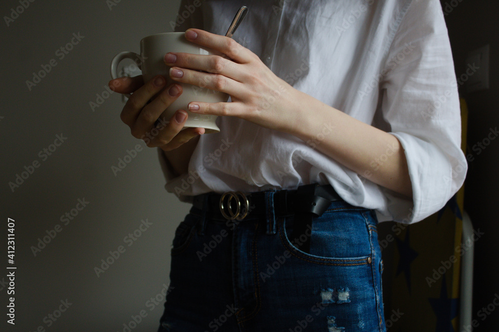 Person with a cup of coffee. Young woman white shirt and jeans hands white cup of coffee