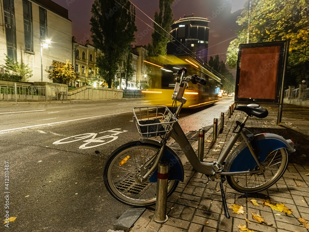 parked bicycle for rent, a yellow bus passes us at speed parked bicycle for rent, a yellow bus passes us at speed
