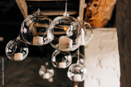 Beautiful hanging glass balls for candles, close-up. Modern wedding decor tendencies. Minimalism. Cozy atmosphere, tree branches