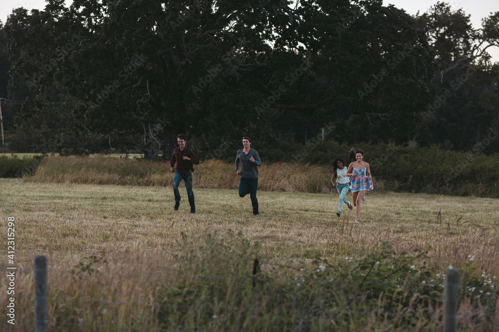 Young friends running in field during summer road trip together