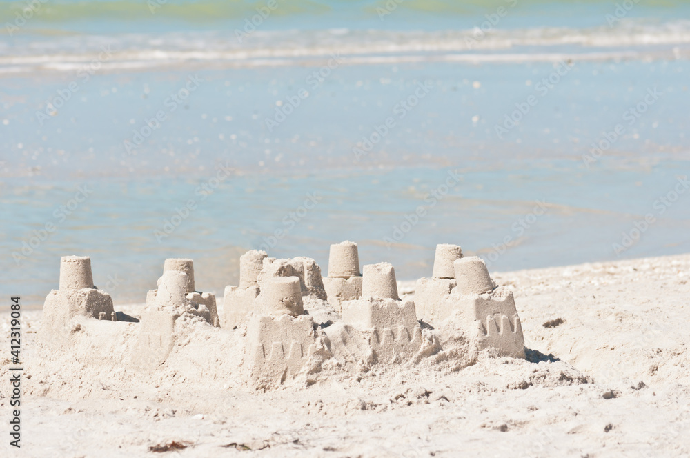 front view of a group of sand castles on a sandy, tropical beach with tropical shoreline and seawater, on a sunny morning