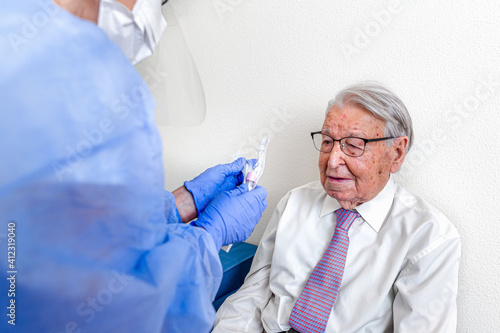 Elderly man watching as a nurse prepares the coronavirus test before performing it.