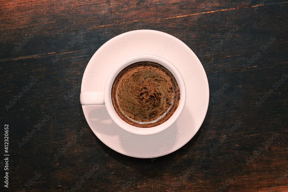 Cup of coffee on brown wooden table. Top view.