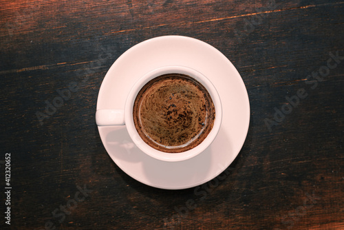 Cup of coffee on brown wooden table. Top view.