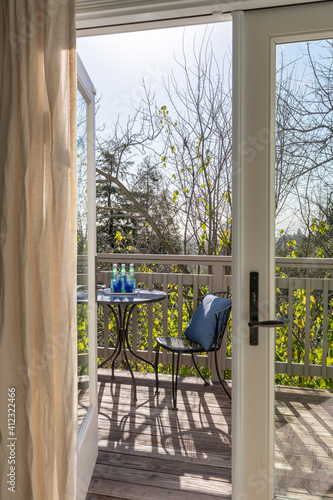 Wallpaper Mural Detail view of double doors opening to wood deck with patio table and chairs and view of nature.  Torontodigital.ca