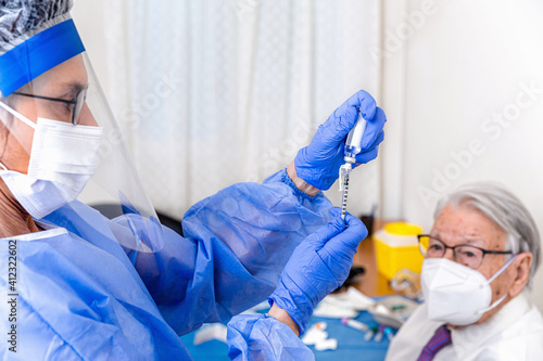 Elderly man watches as nurse prepares his coronavirus vaccine photo