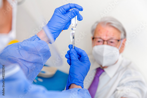 Elderly man watches as nurse prepares his coronavirus vaccine