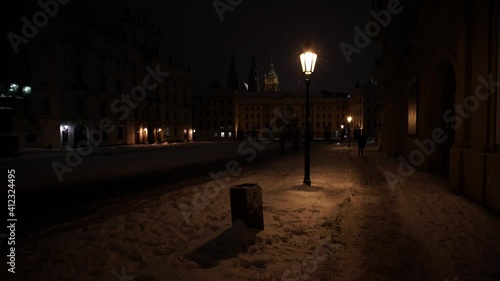 streetlight  at night. In the background on the sidewalk walks silhouettes of people falling snow in the winter 