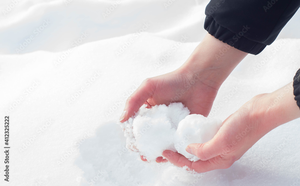 Caucasian hands forming a snowball out of the fresh snow during winter in Europe. Enjoying cold snowy weather after Beast from the East climate change.