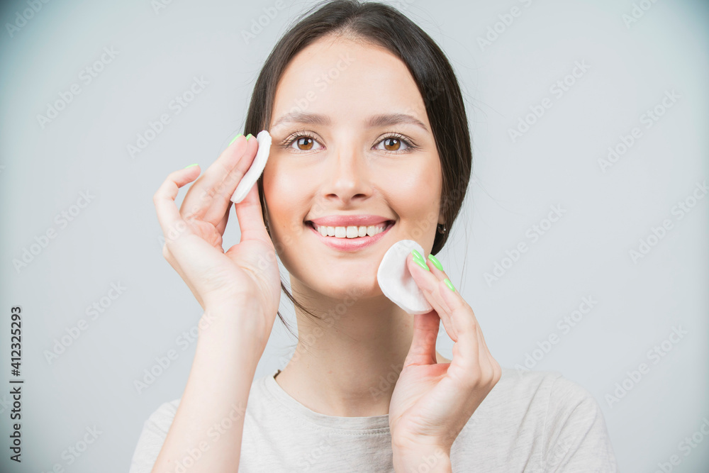 Beautiful brunette woman with a sponge, clean perfect fresh skin using cotton pad skin care concept. Isolated on a white Beautiful brunette woman with a sponge, clean perfect fresh skin using cotton pad skin care concept. Isolated on a white