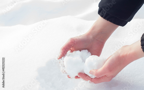 Caucasian hands forming a snowball out of the fresh snow during winter in Europe. Enjoying cold snowy weather after Beast from the East climate change.