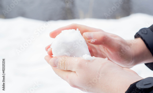 Caucasian hands forming a snowball out of the fresh snow during winter in Europe. Enjoying cold snowy weather after Beast from the East climate change.