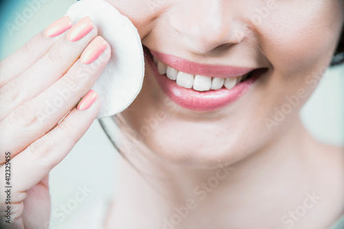 Beautiful brunette woman with a sponge, clean perfect fresh skin using cotton pad skin care concept. Isolated on a white