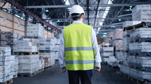 Follow footage of employees male warehouse worker engineer in hard hat working. walking through logistics center warehouse factory construction site logistics architect businessman man builder indoors