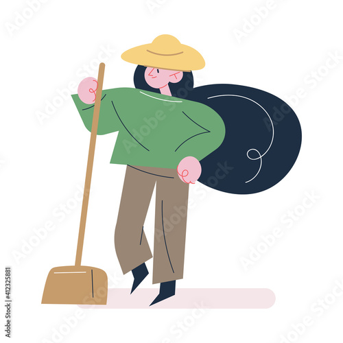 Woman gardener in working clothes and hat standing with shovel