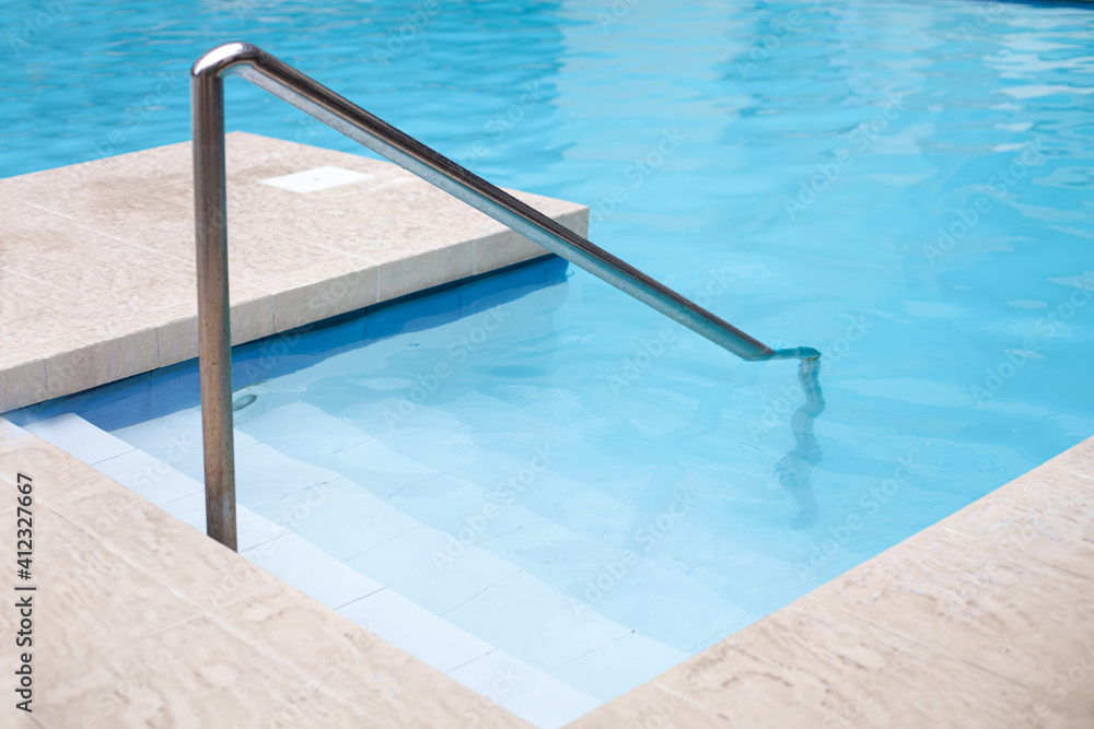 Swimming pool with grab and ladder at poolside